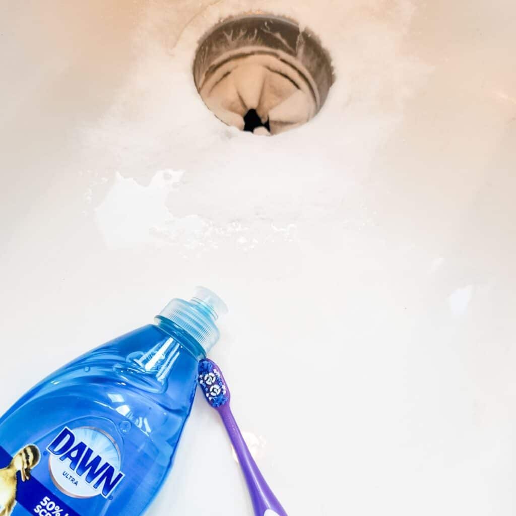 dish soap and a toothbrush sitting in the sink.